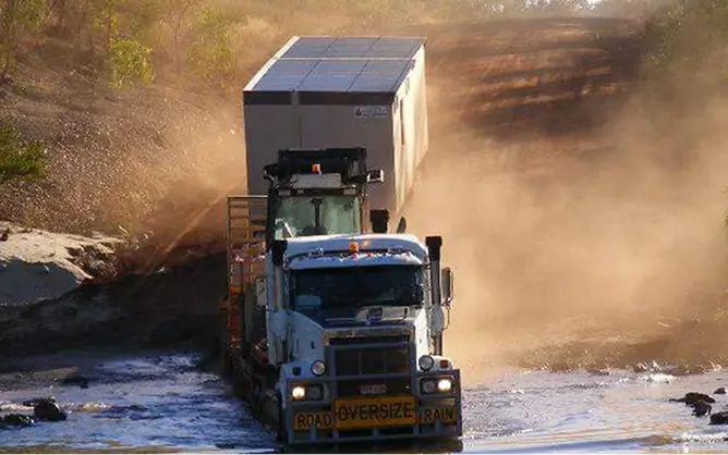 Oversize load truck on a remote dirt road.