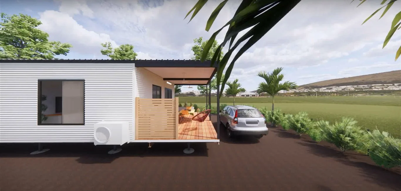 A modern tiny house with a covered wooden porch, outdoor seating, and a car parked beside it. Surrounded by greenery, palm trees, and open fields under a partly cloudy sky.