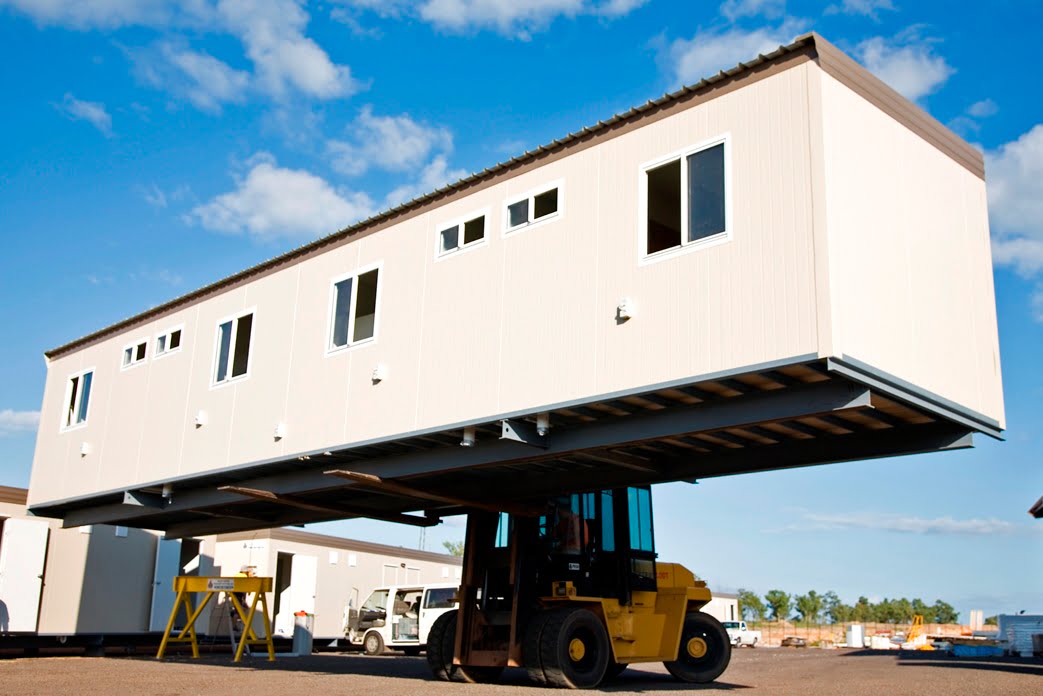Forklift loading a modular building module in the yard