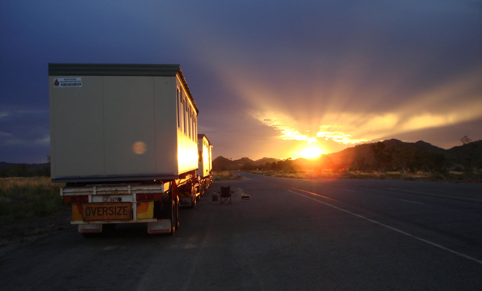 Two Northern Transportables modules on an oversize trailer parked on a remote highway at sunset